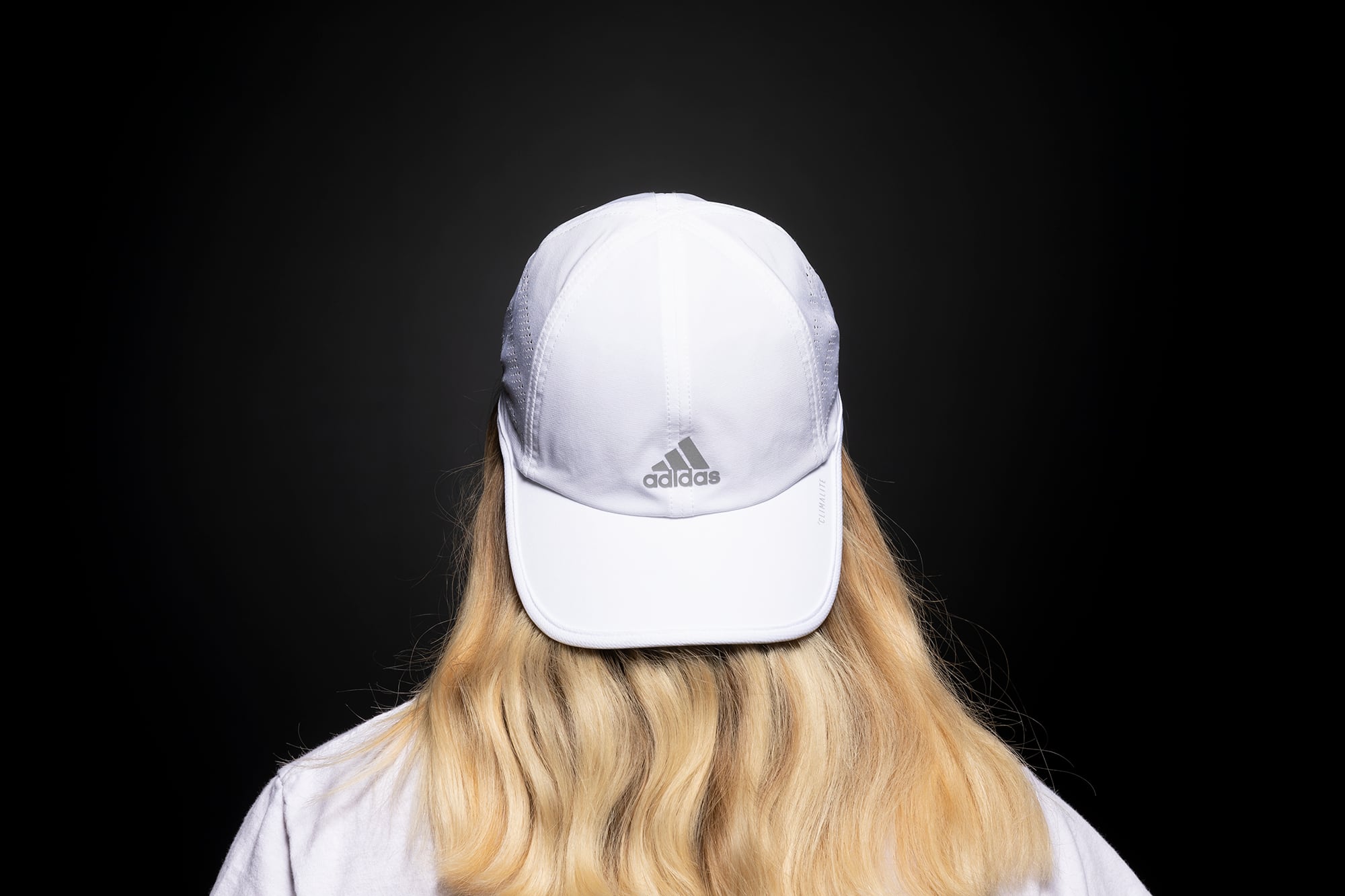 Back of person's head with long blond hair and a white cap turned backwards