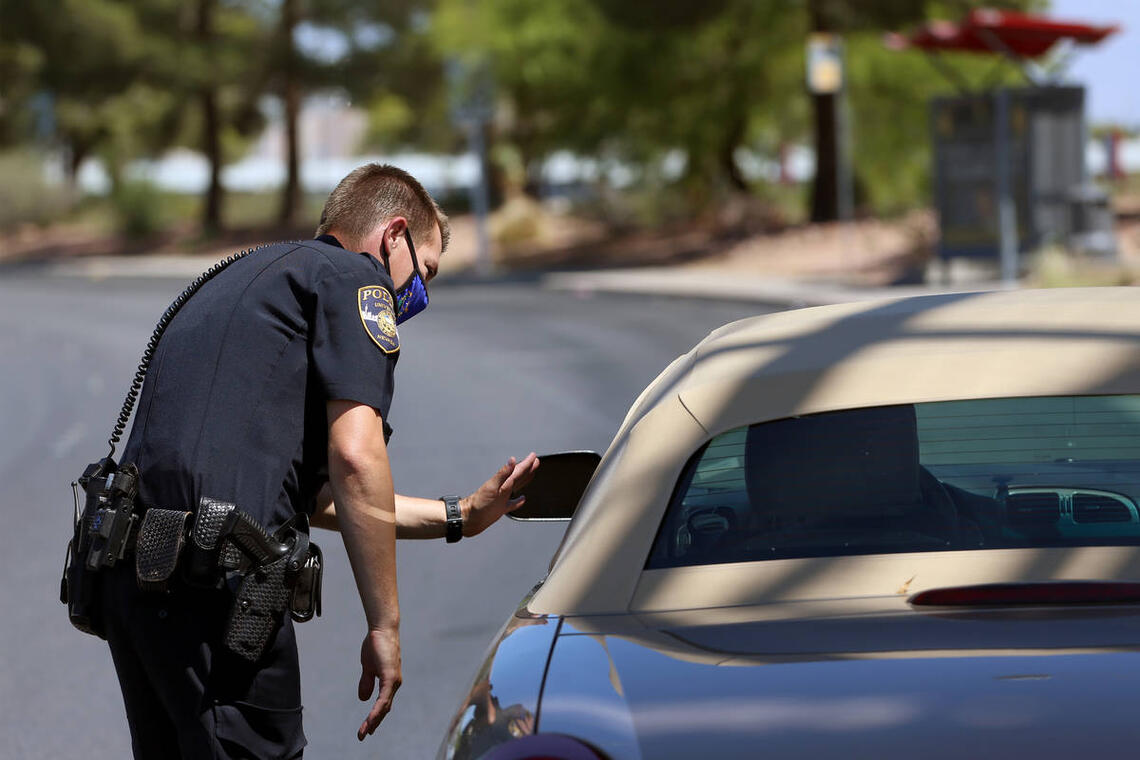 A police officer talking to the driver in the car.