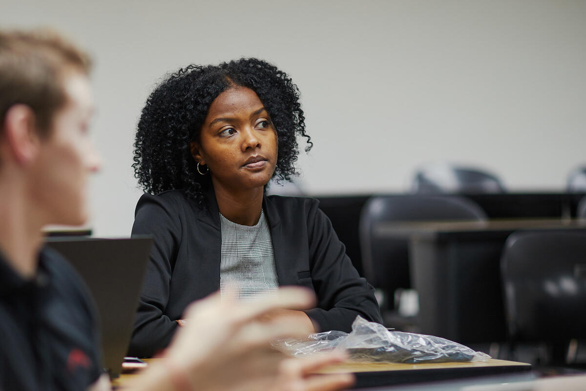 A woman in business attire sitting in an economics class.