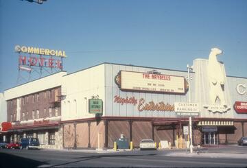 An image of the Commercial Hotel, located at the corner of Idaho Street and 4th Street in Elko. Neon signs on top of the building advertise the Hotel and performances by The Brydells. A large white polar bear statue with the words "White King" is located above the entrance.