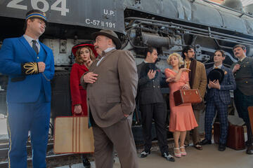 characters from Murder on the Orient Express standing by train