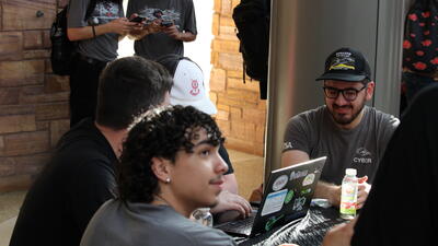 Students sit around laptops and network at conference