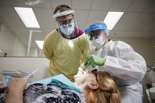Dentist and student dentist providing dental care to a patient.