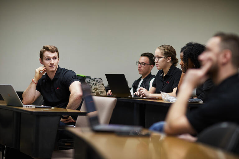 Business students on laptops in a classroom.