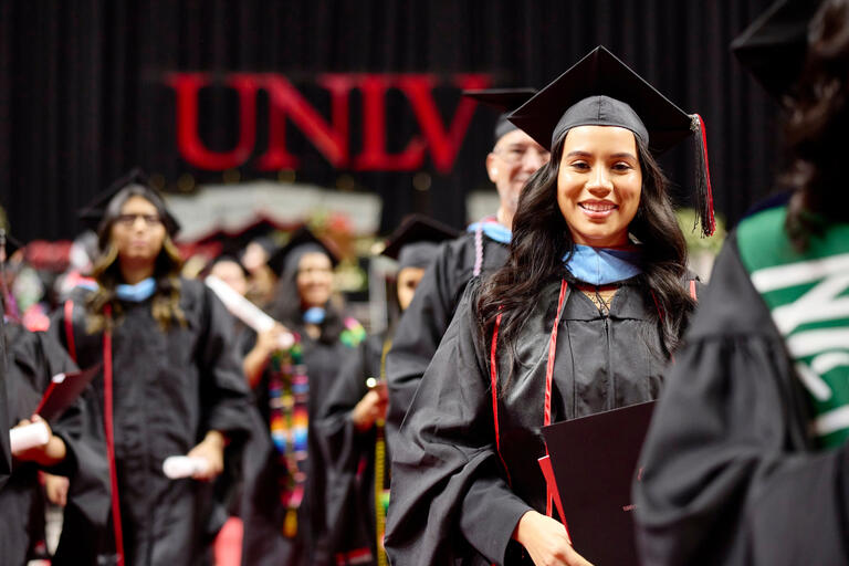 Graduate students at commencement. The UNLV logo is visible in the background.