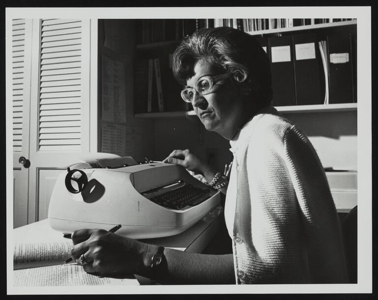 Nevada history women's pioneer Jean Ford sits at her typewriter and looks down as she writes on paper with her left hand