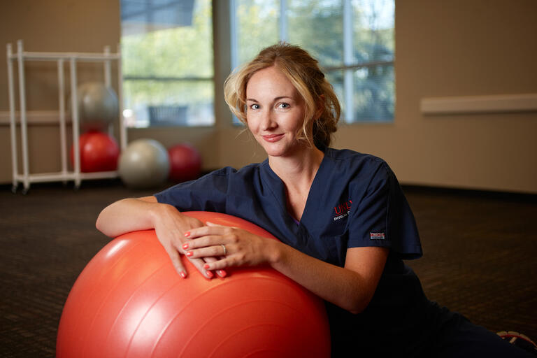 Student posing with a large balance ball
